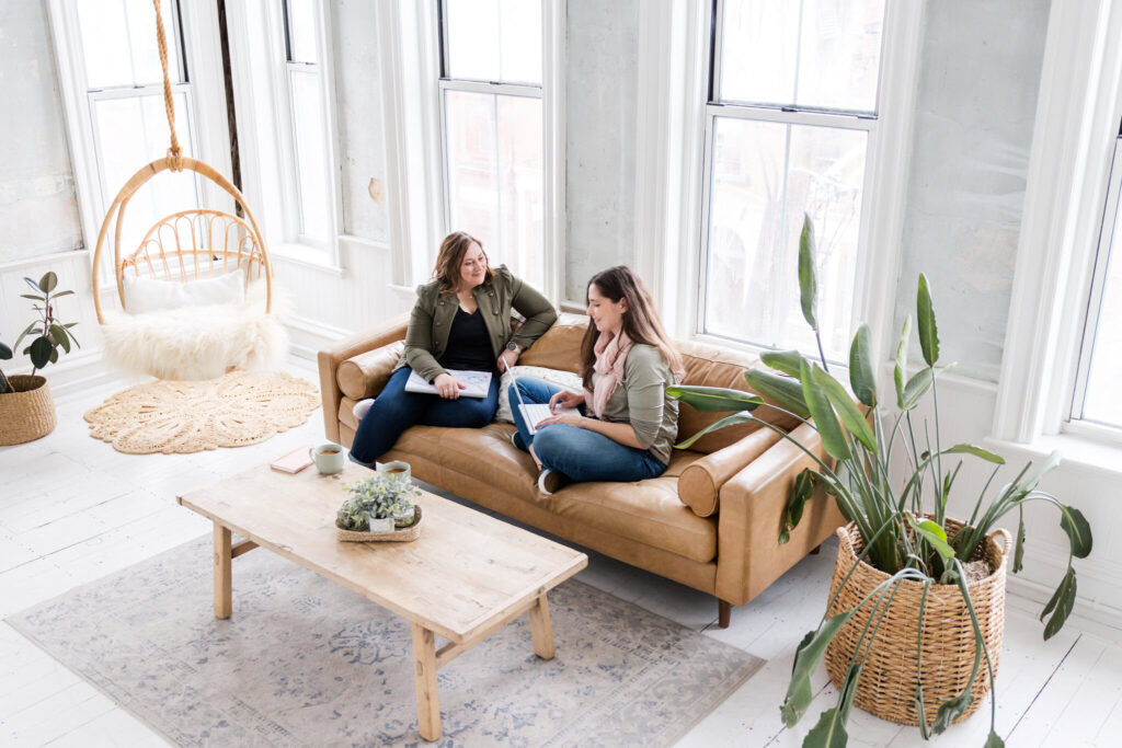 megan and lauren brainstorming for white label seo clients in a trendy room with leather sofa