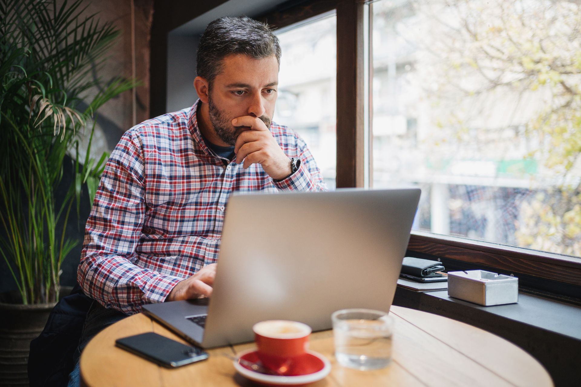 concerned franchise owner looks at a laptop in a coffee shop and stresses over a negative review
