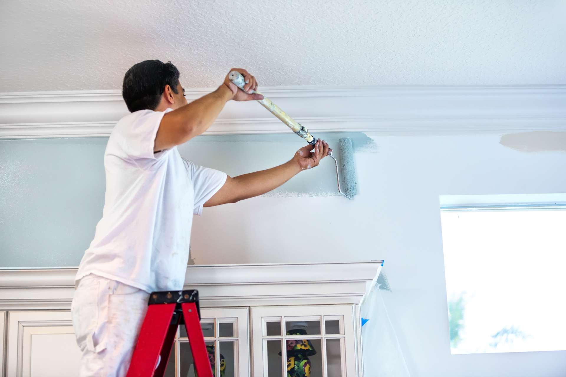 Professional painter on a ladder painting a wall