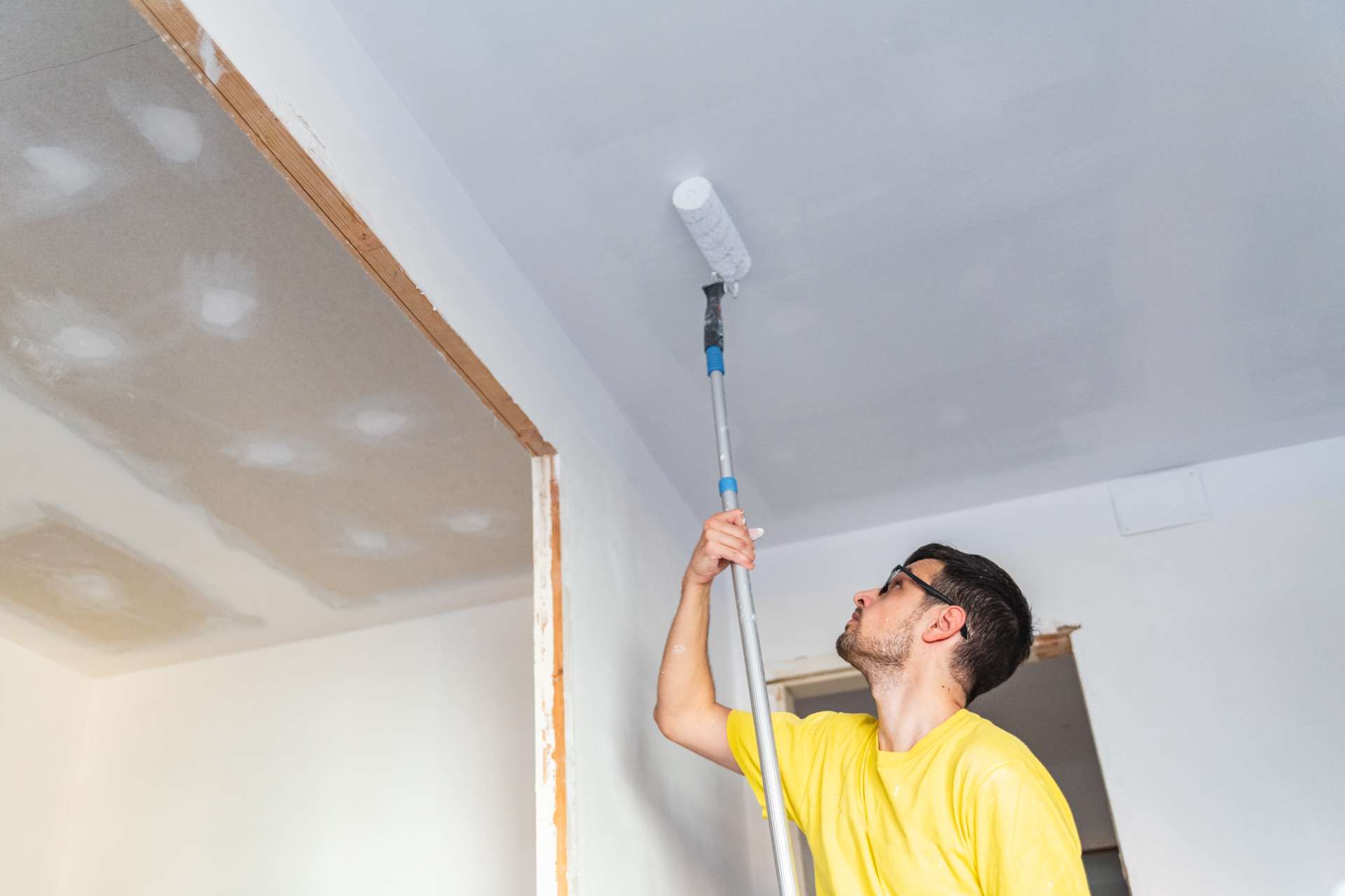 professional painter painting a ceiling in a new construction home