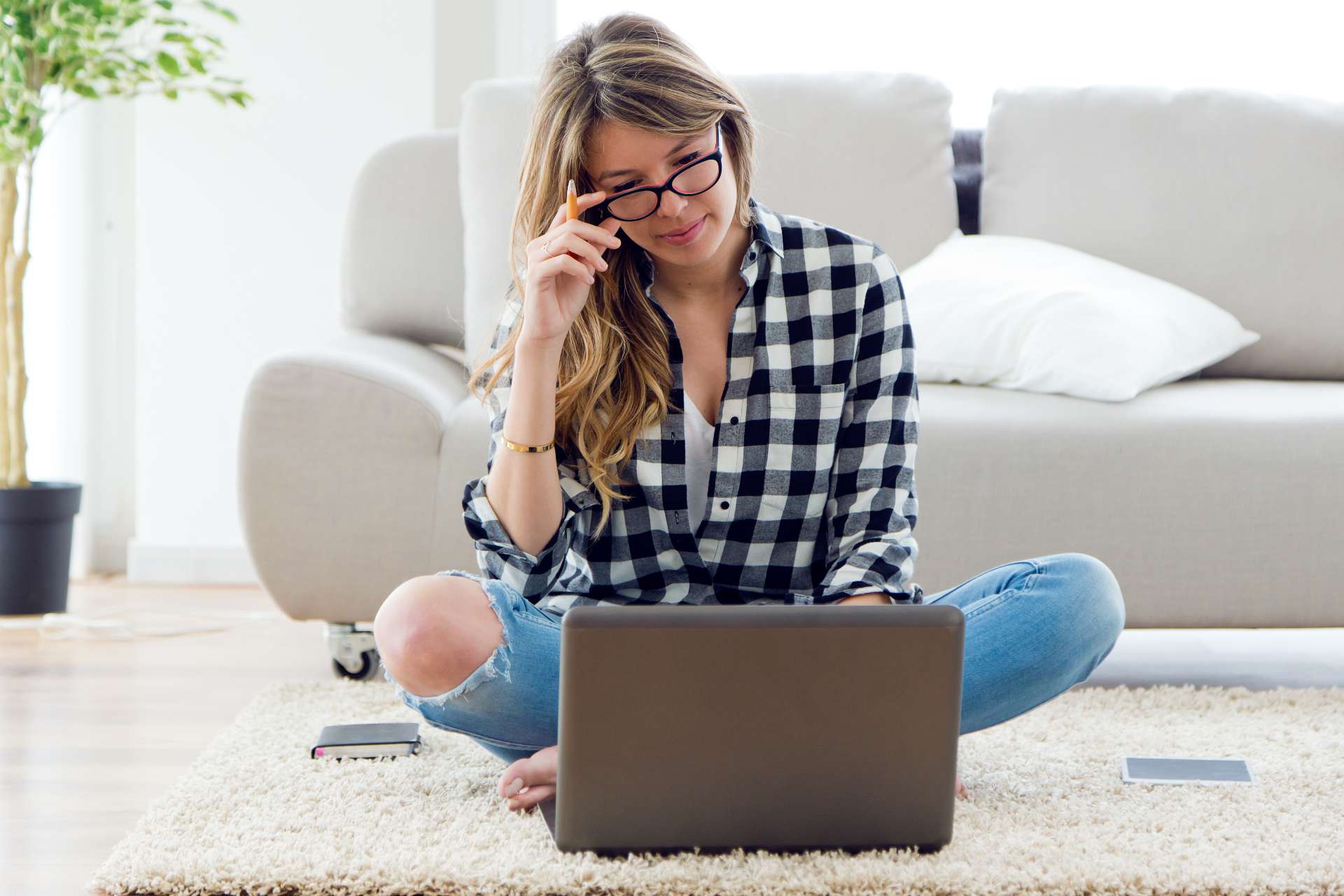 homeowner sitting on floor looking for roofers online on her laptop
