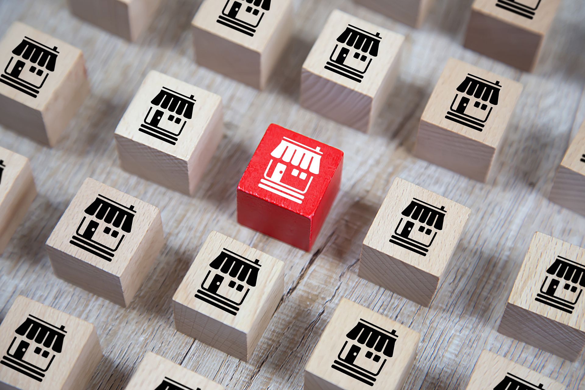 wooden blocks with storefront icons with one red one representing the importance of local franchise content marketing