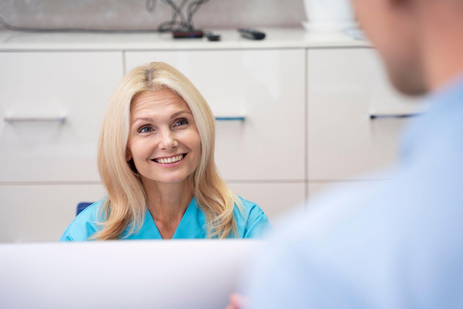 dental receptionist at computer talking to patient