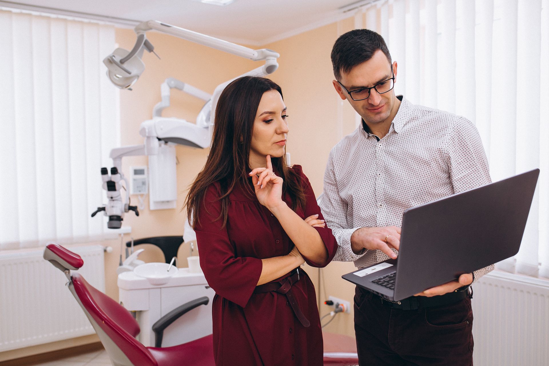 dentist and assistant look at laptop in exam room