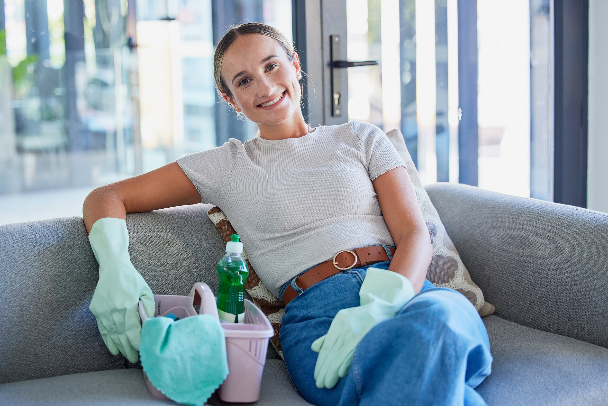 independent cleaning business owner smiling with cleaning supplies