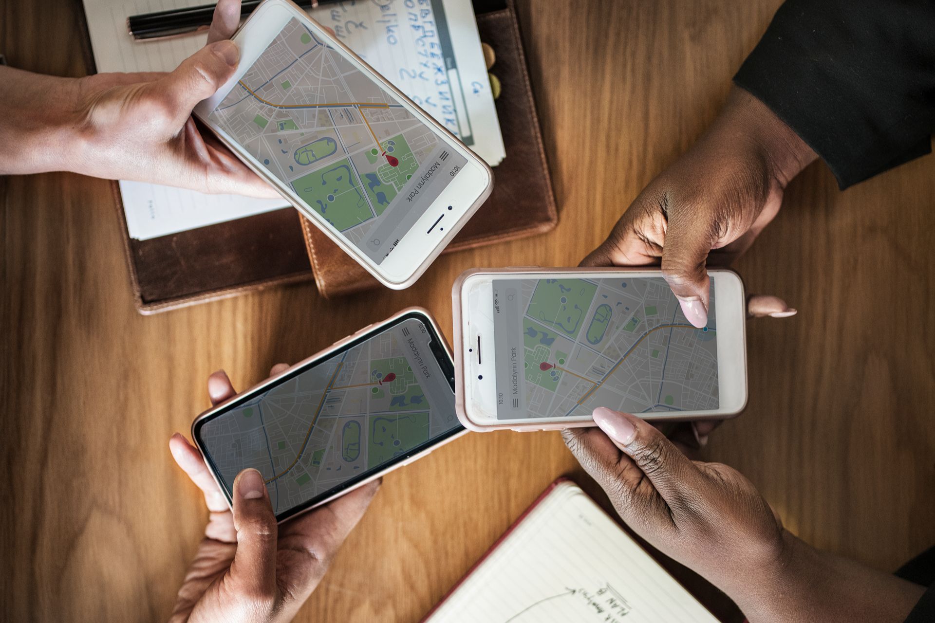 three people holding cell phones looking at maps