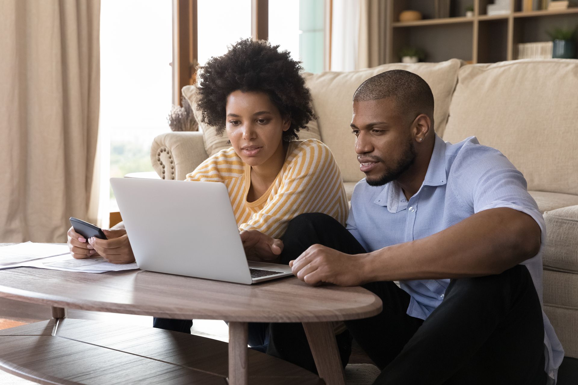 couple exploring online with laptop on coffee table