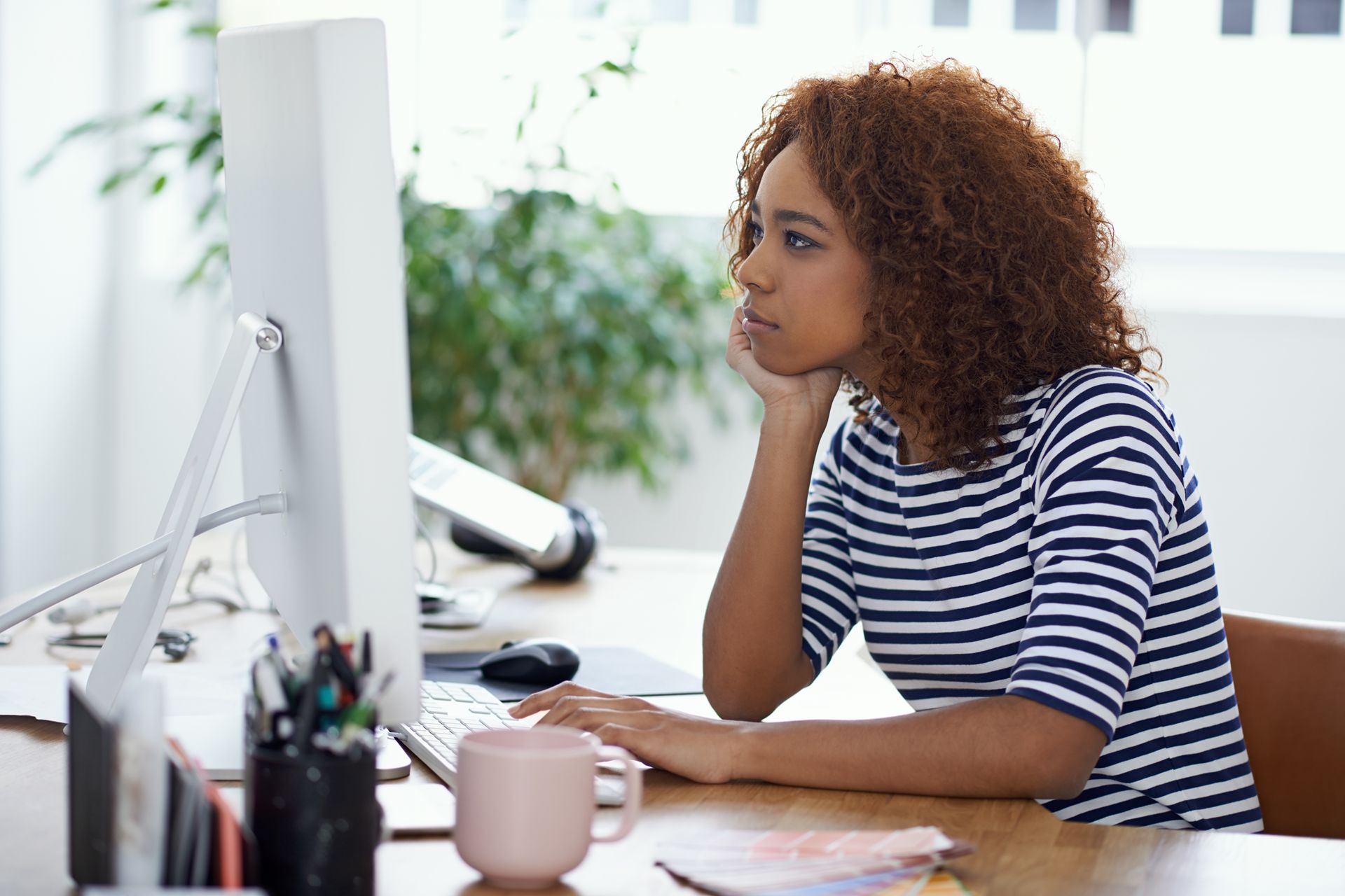 young woman in professional environment searching on computer with a serious expression