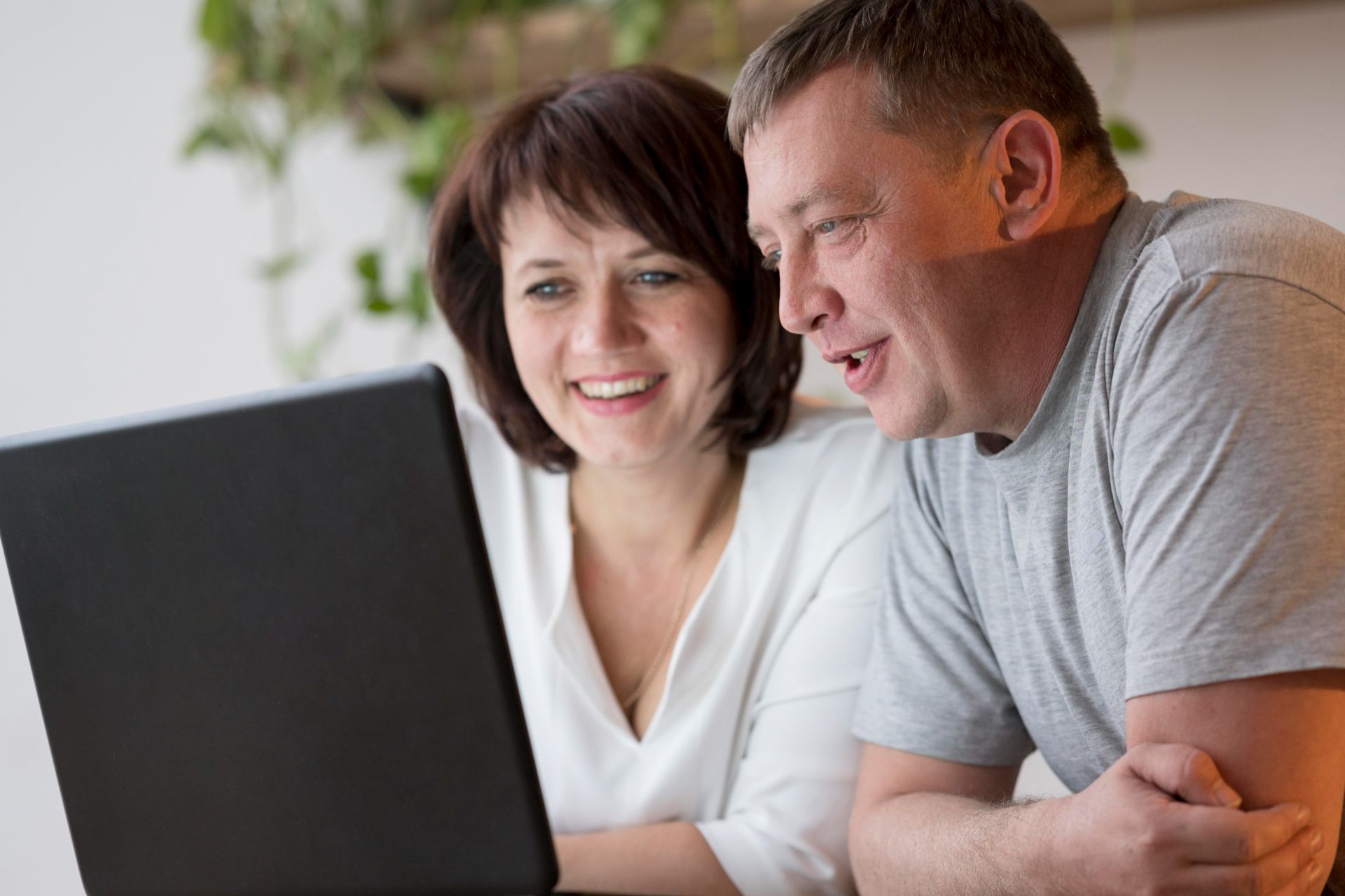 couple smiling looking at laptop together
