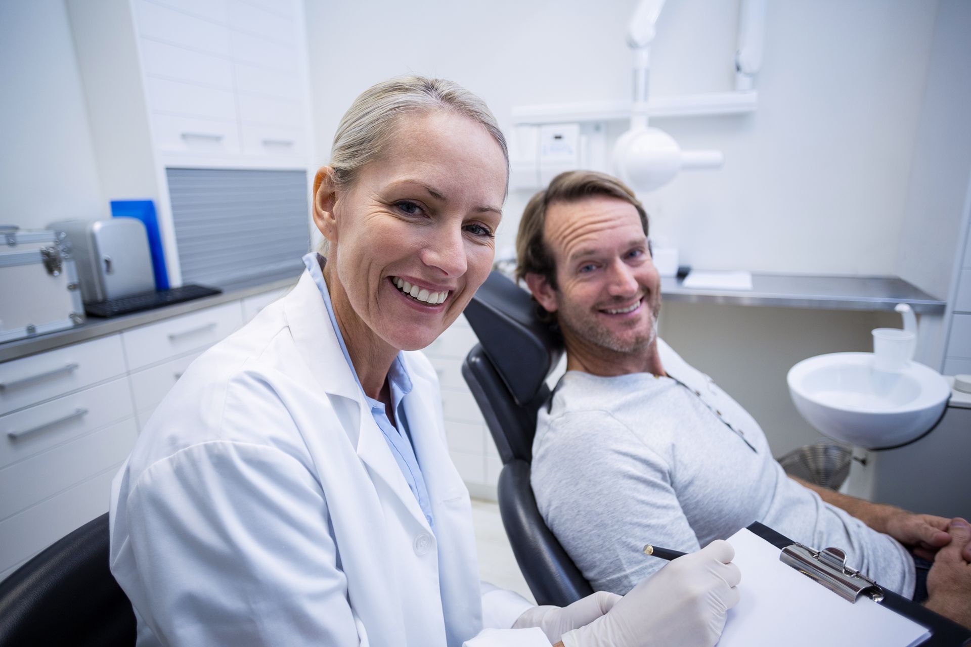 smiling dentist with patient in exam room