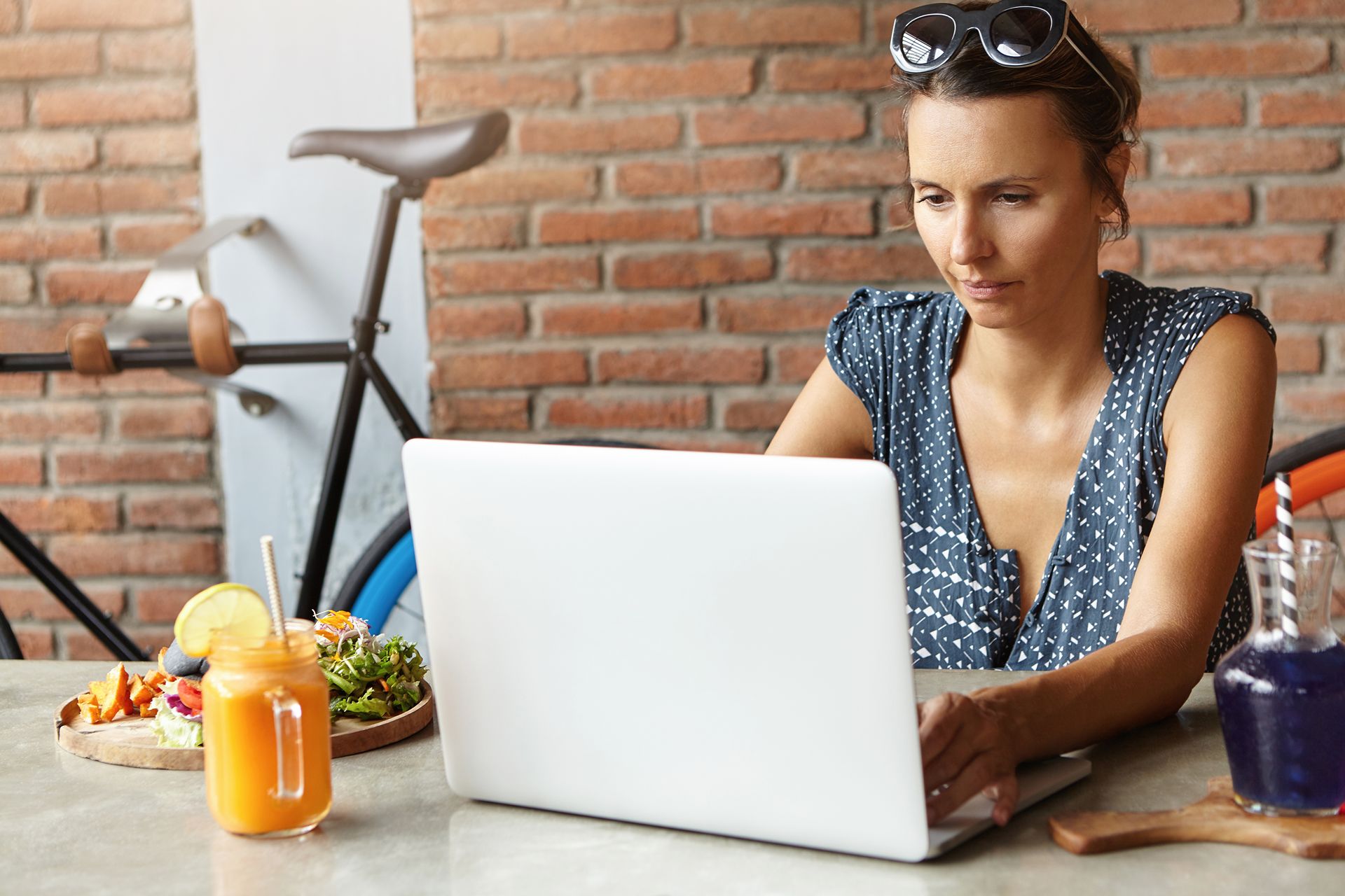 fit woman with healthy meal and bicycle behind her searches online for a new personal trainer