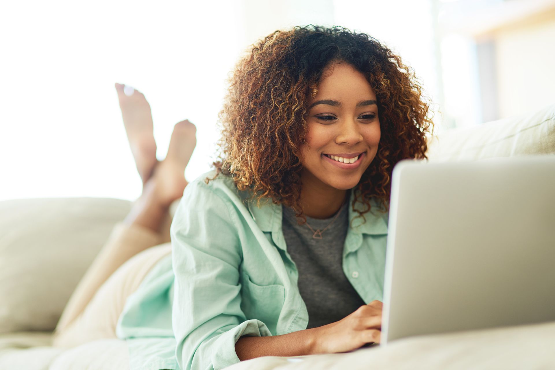 happy woman searching for a yoga studio online while relaxing on sofa