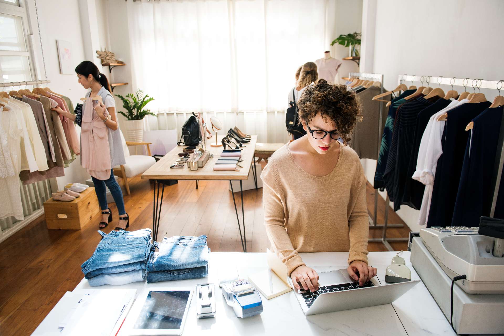 business owner working on laptop in small boutique clothing store