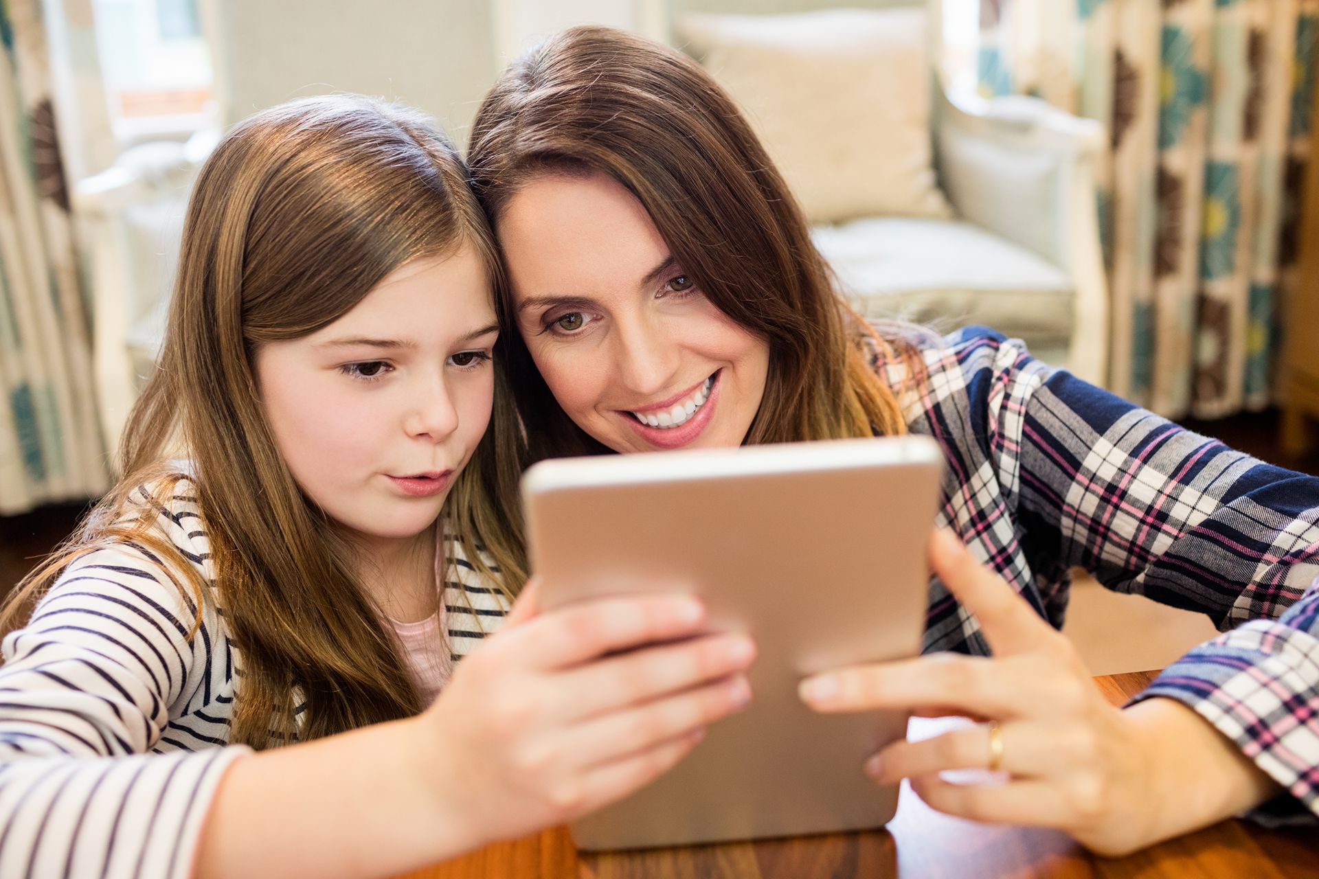 mother looking at child enrichment programs on a tablet with her daughter