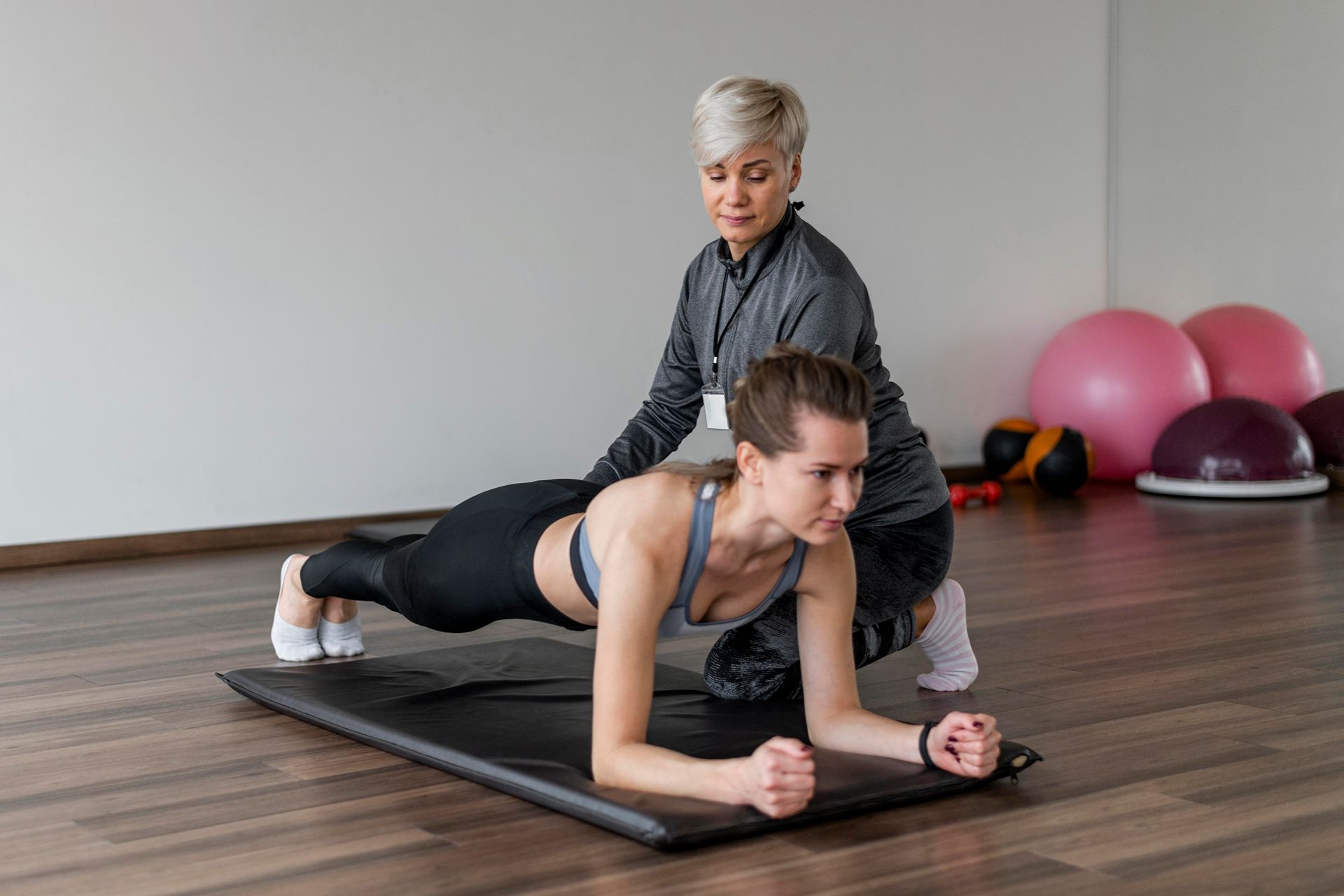 personal trainer supervising a client doing planks