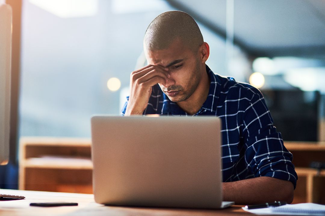 businessman with headache working on DIY website on laptop